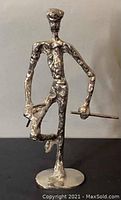 Front view of the vintage handmade cast metal sculpture showing the angry golfer figure with textured body and one leg raised, holding a golf club horizontally.