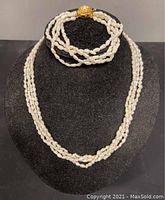 Front view of the freshwater pearl necklace and matching bracelet displayed on a black bust.