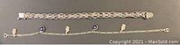 Photo of both sterling silver bracelet and anklet laid flat showing chain details and charms on bracelet.