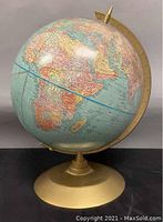 Side view of the globe showing part of the continent of Africa, mounted on a gold-colored round base with semi-meridian arm.