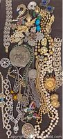 Overview of assorted vintage costume jewelry including necklaces, brooches, faux pearls, and earrings with various metals and stones.