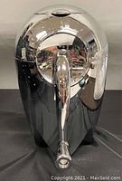 Front view of the chrome ice crusher showing the handle and domed lid with minor wear and some surface tarnish.