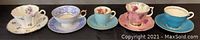 Five assorted demitasse teacups with matching saucers displayed side by side showing front views and decoration details.