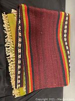 Folded view of the rug runner showing the fringe and side colors including red, green, black, and yellow with woven textures.