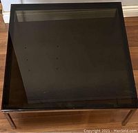 Top view of the smoked glass square coffee table showing surface and metal frame.