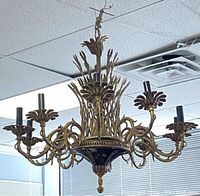 Full view of the brass chandelier hanging from ceiling, showing detailed arms and candle-style holders