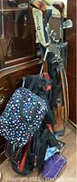 Photo of golf clubs and golf bags, showing a mix of metal and wooden clubs, and two golf bags including one with multicolor dots