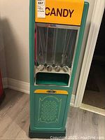 Front view showing yellow “CANDY” signage, five clear tubes, twist knobs, decorative lower panel and casters