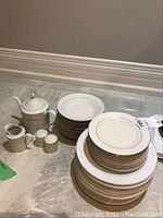 Overall view of all stacked plates, bowls, and the coffee pot set including creamer and shakers