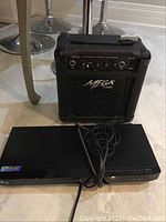 LG BluRay/DVD player and Mega Amp integrated guitar amplifier placed on floor, showing front and top views.