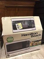 Photo of the Hamilton Beach microwave oven box showing the brand, power of 1000 watts, and 1.1 cu. ft. capacity.