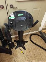 Full view of karaoke machine with control panel on top, pedestal with power cord, and mounted microphones.