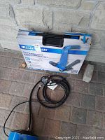 Mastercraft 3 in 1 flooring nailer in original box with power cord coiled beside it on pavement.