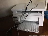 White HP LaserJet Pro MFP M130nw multifunction printer with control panel, paper output tray and cables.