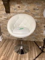 Front view of white faux leather salon chair with button tufted backrest and round chrome base.