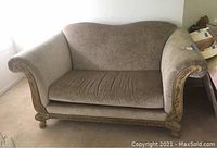 Front view of the brown velour loveseat with carved wood frame and rolled arms.