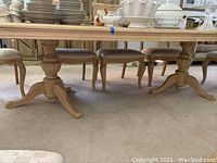 Side angle view of the wooden dining table's pedestal legs and base showing design and finish.