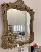 Full view of the hanging mirror showing the carved wooden frame and reflective surface.