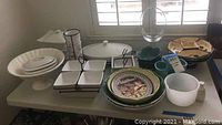Overall assortment of kitchenware including plates, serving dishes, bowls on table