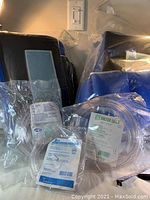 Photo of three clear, individually bagged medical hoses with labels visible, lying on a dark surface.