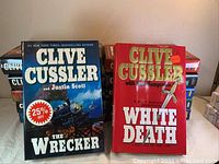 Stack of hardcover Clive Cussler novels showing The Wrecker and White Death covers.