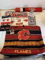 Lot of Calgary Flames souvenirs displayed including scarf, jersey, keychain, pins, flash drive
