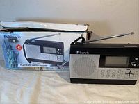 Front view of Bench radio with antenna extended and original box behind.