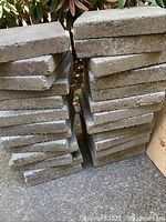 Stack of rectangular concrete paving stones with rough edges and corners, roughly 12x12 inches, showing the lot quantity and condition.