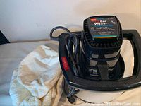 Front view of WEN orbital car waxer with attached power cord and polishing cloths nearby