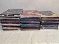 Photo showing stacks of CD jewel cases with visible titles including Alternative, Country and Pop artists