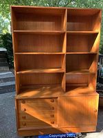 Front view of teak veneer wall unit showing drawers and shelving with sliding door and wooden knobs