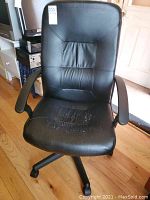 Front view of black office chair showing damage and wear on seat.