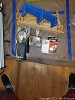 Photo of blue plastic and wooden folding wall hangers alongside bike accessories and lock on fabric surface