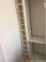 Two photographs showing tall, narrow white CD holders with multiple adjustable shelves. The shelving units are positioned next to each other and against a white wall, highlighting their height and multi-shelf design.