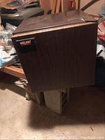 Mini fridge by Welbilt with wood grain exterior, photographed from front showing logo and door.