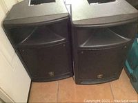 Front view of two Yamaha speaker cabinets side by side showing grilles and Yamaha logos