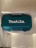 Closed teal Makita plastic case with logo on lid.