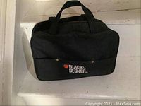 Black & Decker black canvas carrying bag with handles on a white stair surface