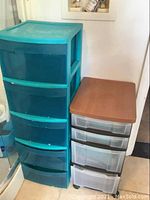 Blue plastic storage container with 5 drawers next to black and clear 4-drawer storage unit with wood-textured top.