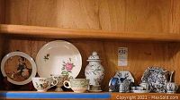 Wide view showing plates, cups, fish figurines and vase on shelf