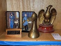 Wide view showing all book ends and plaque including wooden military figures, brass duck, brass eagle on wooden base, and North Pole Water plaque.