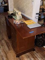 Side view of wooden sewing cabinet with sewing machine on top and some accessories laid out.
