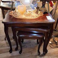 Set of three wooden nesting tables stacked together, good condition, polished finish needing cleaning.