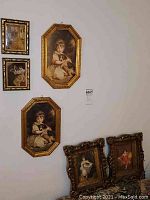 Six framed art prints mounted on a white wall and leaned on the floor showing vintage children's portrait prints and decorative gold and brown frames.