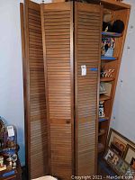 Full view of two wooden shutters standing side by side, showing their size and foldable design.