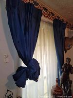 Blue curtain panel shown tied back with fabric tie highlighting the deep blue color and sheen.