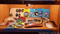 Photo showing multiple souvenir embroidered patches, bead bracelets, metal nail clippers, wooden shoehorn, and other small accessories arranged on a wooden surface.