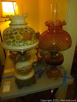 Photo showing both lamps side by side on a gray table with various dishes in the background.