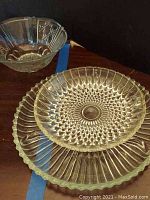 Three clear glass hostess serving pieces with ribbed, hobnail, and fluted designs shown on wood surface under soft lighting.