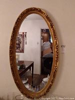 Full view of oval mirror hanging on wall showing entire frame and reflected room.